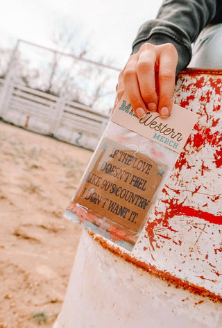 90's Country Car Air Freshener packaging held by a person, featuring a quote about love resembling the essence of 90s country music, ideal for country music enthusiasts.